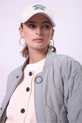 Campera acolchada color gris claro, con cuello mao y cierre frontal con botones a presión. Tiene bolsillos laterales y corte holgado.