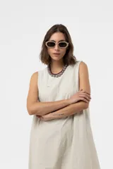 Vestido midi de silueta amplia y relajada, sin mangas, con escote redondo y costuras decorativas. Presenta una falda con corte y volumen.