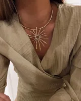 Gargantilla rígida dorada con dije en forma de sol con rayos irregulares plateados.
