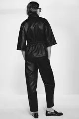 Pantalón tobillero de tiro medio color marrón oscuro, con cintura elástica ajustable con cordón y herretes dorados. Incluye bolsillos delanteros y bolsillos de plastrón en la espalda.