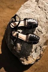 Sandalias cangrejeras color rojo con detalles de tachas doradas y correa con hebilla al tobillo.