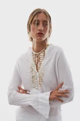 Collar tipo pechera confeccionado con múltiples tiras de discos de nácar en tonos blancos y marfil, unidas a una estructura corta de cuentas tubulares.