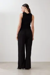 Pantalón de corte amplio y tiro medio, confeccionado en tejido suave de color negro. Presenta una cintura elástica con cordón ajustable y bolsillos laterales amplios.