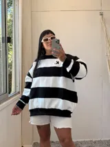 Buzo oversize de tela deportiva con felpa, a rayas horizontales negras y blancas, con cuello redondo y logo pequeño bordado en el pecho.