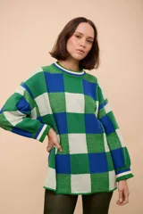Buzo oversized de punto texturizado, con diseño a cuadros en tonos de verde, azul y blanco. Tiene cuello redondo y puños acanalados.