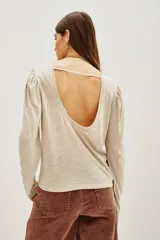 Remera de viscosa en color beige, de manga larga con detalle de frunces en los hombros y un pronunciado escote en la espalda con tira horizontal.