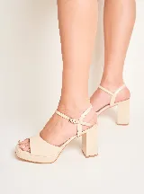 Sandalia de fiesta color beige, confeccionada en cuero, con pulsera fina al tobillo y hebilla dorada. Cuenta con taco de 9 cm y plataforma de 2 cm.