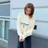Sweater Nude Project de punto color beige, con cuello redondo y diseño de corte regular. Presenta el logotipo de la marca y la frase 'by artists for artists' bordados en el pecho, junto con un pequeño diseño de cerezas en color rojo.
