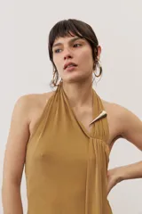 Vestido largo negro de corte al cuerpo con cuello halter y detalle de hebilla metálica dorada en el hombro con tira drapeada.