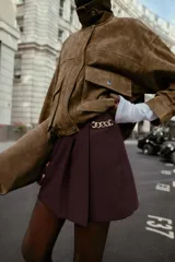 Bermuda de tiro alto color negro, con diseño de tablas frontales y detalle de eslabones metálicos dorados en la cintura. Cuenta con cierre lateral oculto.