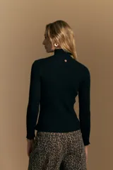 Polera de tejido acanalado con cuello alto, corte ajustado al cuerpo y mangas tres cuartos con terminaciones onduladas en los puños.