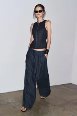 Pantalón culotte de denim azul oscuro, tiro medio, con cintura elástica en la parte trasera, bolsillos laterales y pinzas delanteras. Cierre frontal con cremallera, botón y ganchos metálicos.