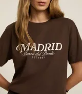 Remera marrón de algodón con cuello redondo y mangas cortas. Estampado frontal con la leyenda "Madrid Museo del Prado EST 1987" en color blanco.
