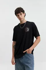 Remera negra de manga corta con cuello redondo y fit regular. Presenta un estampado frontal con gráficos circulares y texto en blanco y naranja.