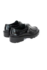 Mocasín de plataforma estilo track, confeccionado en cuero vacuno con acabado charol brillante. Presenta una puntera redondeada, suela robusta antideslizante y un detalle de tira con apliques metálicos en el empeine.