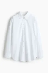 Camisa blanca de corte relajado, cuello clásico, mangas largas y cierre frontal con botones.