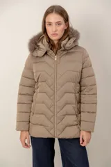 Campera corta capitoneada con diseño de costuras en zigzag, cierre frontal y capucha desmontable con borde de piel sintética. Cuenta con bolsillos laterales con cierre.