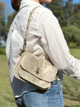 Cartera tipo bandolera con diseño de acordeón, color dorado con acabado metalizado. Cuenta con solapa frontal con cierre metálico giratorio y doble correa, una de ellas ajustable mediante broches a presión.