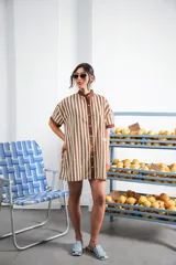 Vestido camisero corto, con cuello mao, botones a tono y parche con logo en el frente. Diseño a rayas verticales negras y blancas.