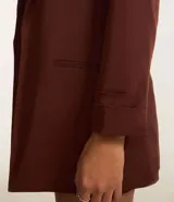 Blazer de sastrería color bordó, de corte oversized y largo, confeccionado en crepé. Presenta solapas clásicas, bolsillos frontales y detalle de pliegues en los puños.