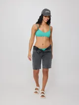 Top de bikini con tirantes finos y escote redondo, confeccionado en poliamida con elastano, con estampado tropical en tonos verdes, celestes y salmón sobre fondo negro.