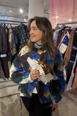 Camisa de popelina azul con estampado toile de jouy, cuello clásico y cierre frontal con botones. Presenta un diseño ajustado en la cintura mediante cordones laterales estilo corset y mangas largas abullonadas.