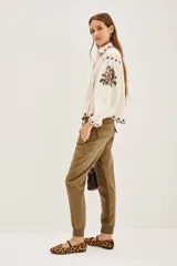 Pantalón tipo babucha de gabardina elastizada, color negro, con cintura elástica ajustable mediante cordón, puños en los tobillos, bolsillos diagonales frontales y bolsillos traseros con solapa y botón.