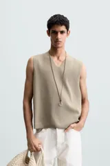 Chaleco de punto color beige claro, con cuello en V y corte relajado sin mangas.