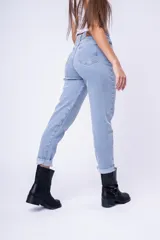 Pantalón de jean estilo mom fit, de tiro alto y corte recto con ruedo doblado. Presenta un lavado claro, cierre frontal con botón y bolsillos laterales y traseros.