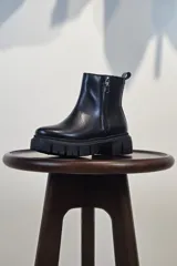 Bota de caña corta color marrón, con cierre lateral y suela track negra de goma con plataforma.