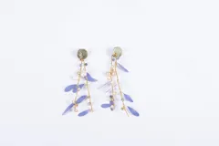 Aros colgantes dorados con forma de rama, con hojas violetas y cuentas de cristal blancas, celestes y doradas.