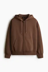 Campera con capucha H&M de corte oversized, confeccionada en tejido pesado de mezcla de algodón con interior cepillado. Presenta cierre frontal, hombros caídos, capucha forrada con cordón de ajuste y bolsillos tipo canguro. Puños y bajo acanalados.