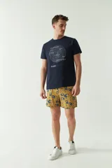 Short de baño estampado con diseño floral en tonos azul sobre base mostaza. Cuenta con cintura elástica con cordón de ajuste, dos bolsillos laterales y un bolsillo trasero.