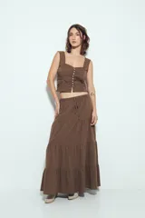 Top corto color marrón, con escote cuadrado y breteles anchos con volados. Presenta frunces horizontales en el torso y una hilera de botones nacarados en el centro frontal.