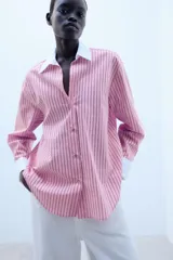Camisa de rayas rosas y negras, con cuello solapa y puños anchos en color blanco. Presenta mangas largas, bajo asimétrico y cierre frontal con botones.