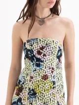 Vestido corto de silueta strapless y calce ajustado, confeccionado en encaje estampado con diseño floreado sobre base amarilla. Está forrado íntegramente en poplín y presenta recortes de entalle en el delantero y la espalda.