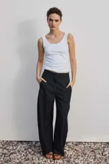 Pantalón de vestir de corte ancho y relajado, color negro con sutiles rayas diplomáticas verticales. Presenta bolsillos laterales y cierre frontal oculto.