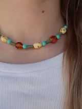 Collar de cristales multicolor con cuentas en tonos ámbar, verde, celeste y beige con pequeñas manchas.