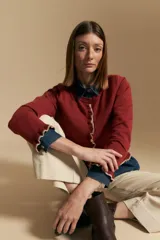 Cárdigan de manga larga color bordó, de tejido liviano y suave, con volados en el delantero, ruedo y puños en color beige. Cierre frontal con botones.