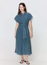 Vestido midi de corte recto color azul, con cuello camisero, mangas cortas y cierre delantero con botones ocultos. Incluye un cinturón ajustable del mismo tejido para anudar en la cintura.