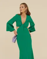 Vestido largo color verde esmeralda, con escote en V, corte a la cintura y falda con abertura lateral. Mangas largas acampanadas y espalda descubierta.