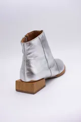 Botín de cuero dorado con punta fina y taco bajo cuadrado de madera.