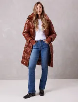 Campera puffer larga de abrigo marca BCBG Maxazria, color beige. Cuenta con capucha desmontable, cuello alto envolvente, cierre frontal bidireccional con solapa de botones a presión, bolsillos laterales, puños internos elastizados y tajos laterales con cierre en el bajo.