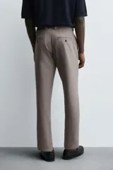 Pantalón chino de corte slim fit, confeccionado en tejido elástico. Presenta bolsillos frontales, bolsillos traseros de vivo con botón y cierre frontal con cremallera y botón.