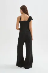 Blusa negra de poliéster con cuello en V, tirantes anchos y un diseño asimétrico con volados escalonados en un hombro. Corte entallado.