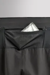 Pantalón de jogging negro confeccionado en tejido técnico ligero y elástico, corte slim fit, con cintura elástica ajustable con cordón, bolsillos laterales y trasero con cierre de cremallera, bandas reflectantes en las piernas y bajos ajustables con cremallera.