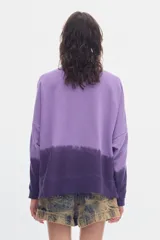 Buzo de felpa sin frisa color lila y morado con efecto degradé, cuello redondo, mangas largas y fit relajado. Incluye bordado pequeño en el centro del pecho.