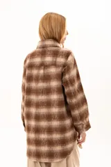 Chaqueta de textura suave y afelpada con diseño de rayas horizontales en tonos beige y marrón. Presenta cuello camisero, cierre frontal con botones y mangas largas con puños abotonados.