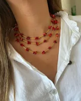 Collar de tres hilos con cuentas de piedra color rojo y detalles dorados.