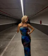 Vestido largo ajustado al cuerpo, con estampado abstracto en tonos azules, negro y rojo. Presenta tirantes finos y recortes laterales que dejan ver la piel.